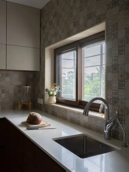 The kitchen features a window over the sink, bringing in natural light and a view of the outdoors. The patterned tiles add character without overwhelming the small space.