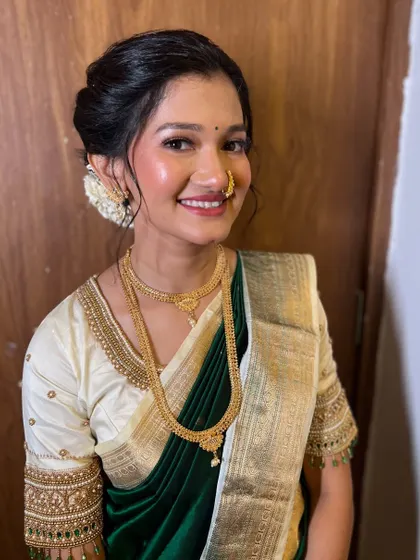 A classic portrait for an engagement ceremony. The bride looks serene and beautiful in her dark green saree and off-white blouse, with a soft glam makeup look.