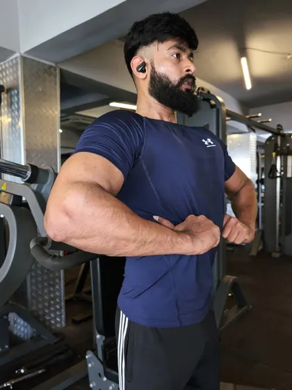 A side chest and bicep pose, highlighting the definition and separation between muscle groups.