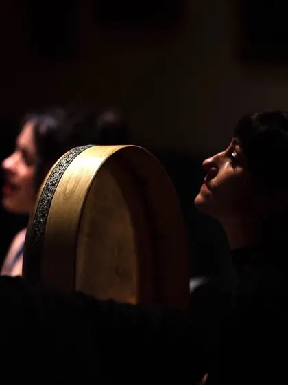 A side view of our artists during a performance, their faces illuminated in the dark. This atmospheric shot conveys the deep listening and connection between the musicians on stage.