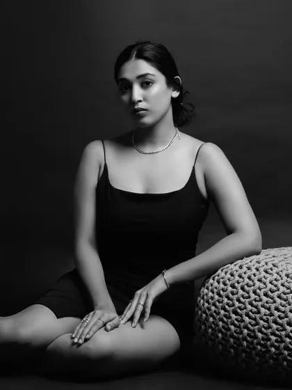 A seated black and white portrait that plays with shadows and form. The composition is simple yet powerful, focusing on the model's elegant posture.