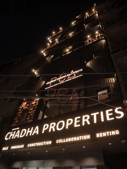 A low-angle night shot of the Chadha Properties office, emphasizing the verticality of the building and the impact of the illuminated signage.