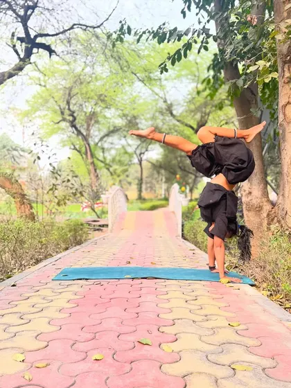 Finding joy in the daily routine. A static image of a one-handed handstand variation in a park, a moment of playful exploration and gratitude for the ability to move.