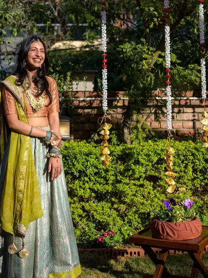The bride, wearing her grandmother's heirloom lehenga, enjoying her simple and beautiful backyard Mehendi.