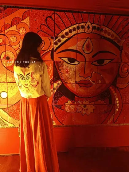 My art meets traditional art. Here I am in my hand-painted Durga jacket, standing before a magnificent Durga mural. It’s a beautiful moment of connection between my wearable art and larger-than-life festive decorations.