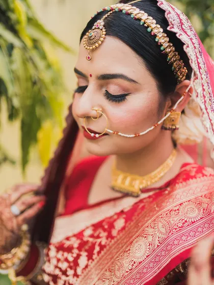 A close-up of the bride's face, highlighting her beautiful makeup and traditional nath (nose ring).
