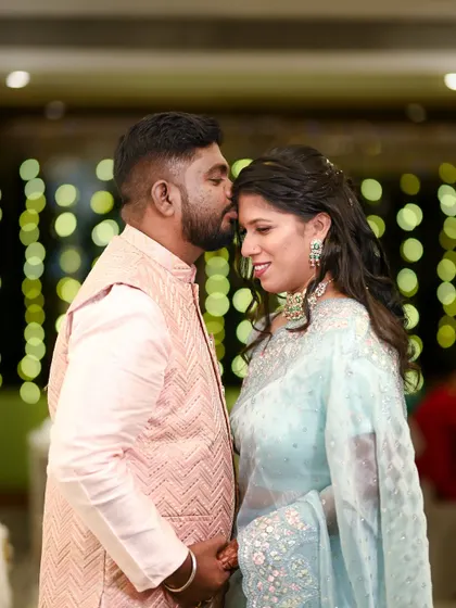A tender moment as the groom kisses the bride's forehead. The soft bokeh lights in the background add a magical and romantic quality to the photograph.