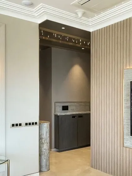 Texture and lighting are paramount in this Art Deco-inspired space. Fluted wall panels create a subtle rhythm, while a classic glass wall sconce provides warm, ambient light.