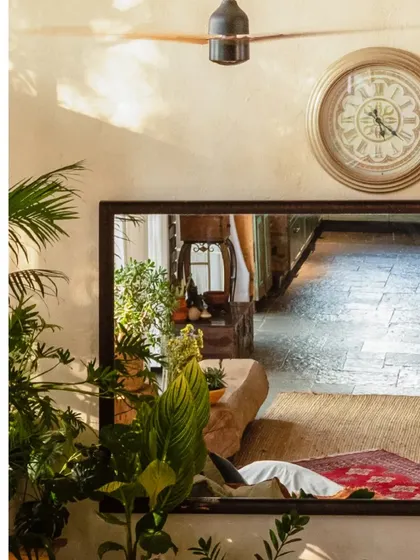 A large mirror reflects the living space, creating a sense of depth and showcasing the interplay of different rustic elements and textures.
