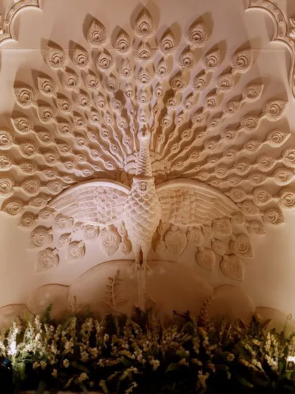 A magnificent hand-carved panel of a peacock, a symbol of grace and beauty in Indian culture. This custom piece served as a breathtaking backdrop and a major focal point for the event.