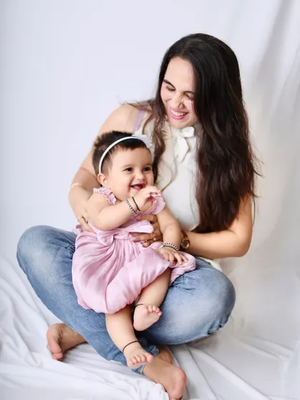 A relaxed and candid photo of a mother and her baby girl sharing a laugh on the studio floor.