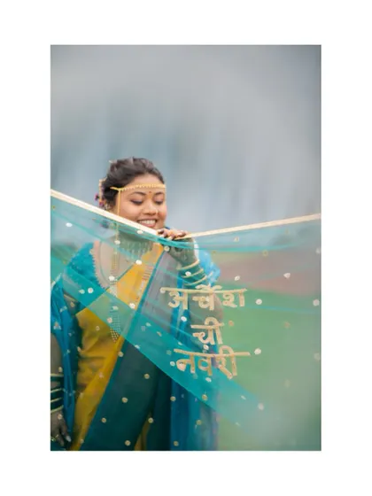 A creative portrait of a Maharashtrian bride with a custom veil that reads 'Archesh chi Navri' (Archesh's Bride) in Marathi.