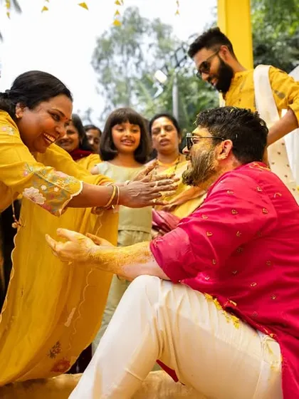 The groom shares a laugh with his family as they apply turmeric paste during the Haldi ceremony.