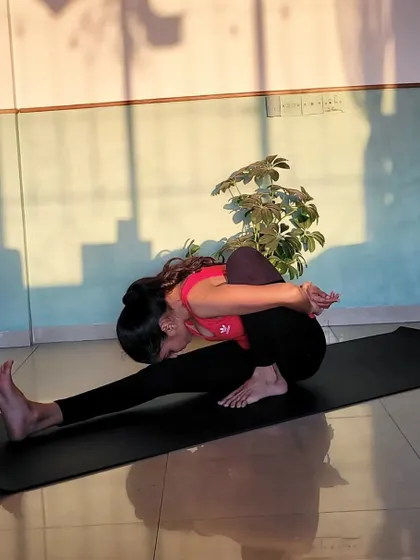 Practicing Marichyasana A, a deep forward fold that stretches the back and shoulders while cleansing the internal organs.