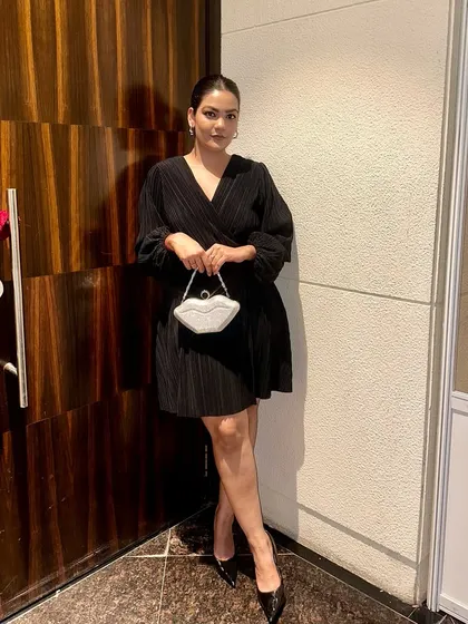 A classic little black dress with a twist. This pleated wrap dress is paired with a quirky, shimmering lip-shaped clutch for a fun party look.