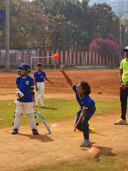 A girl bowls to a batsman during a practice match. This image highlights our inclusive environment where boys and girls train and compete together, fostering mutual respect.