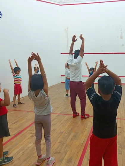 More than just games, it's about building a foundation. Young children participate in a warm-up stretch in an indoor court, learning the importance of preparation.