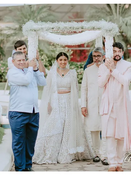 A beautiful bride making her "Din Shagna Da" entrance under a delicate floral canopy held by her brothers and father.