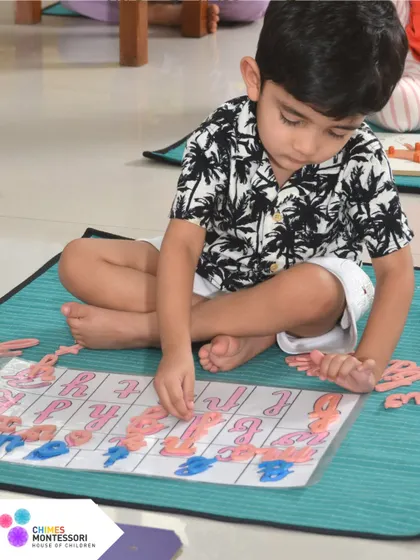 A child works with the movable alphabet, a foundational tool for learning to read and write. This tactile method allows children to form words before they can even hold a pencil.