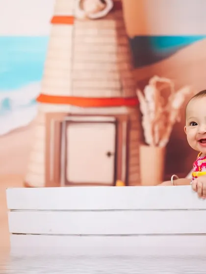 Peeking over the edge of the prop, this baby is full of curiosity during her beach-themed photoshoot. These playful moments make for the cutest pictures.