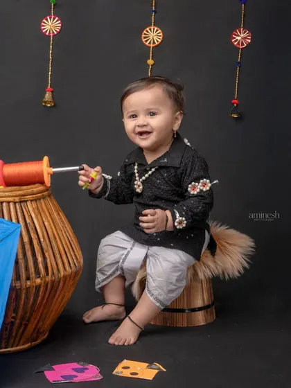 This little one is all set for the kite festival, sitting with his kite and firki. The black outfit is traditional for Makar Sankranti in Maharashtra.
