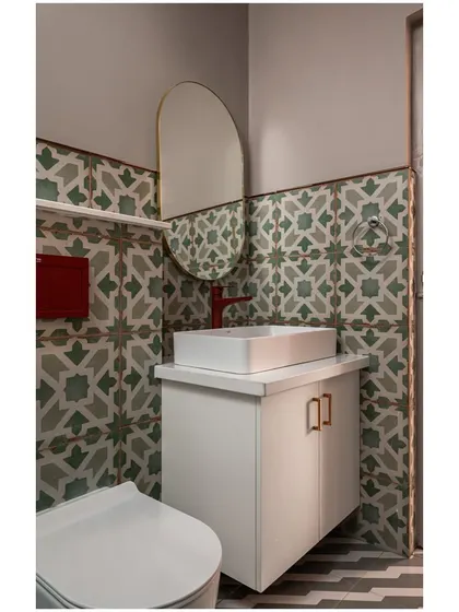 Bathrooms are a great place to play with pattern and color. In this powder room, we used vibrant green and grey geometric tiles to create a feature wall. The pop of the red faucet adds a surprising and playful contrast, turning a small, functional space into a design moment.