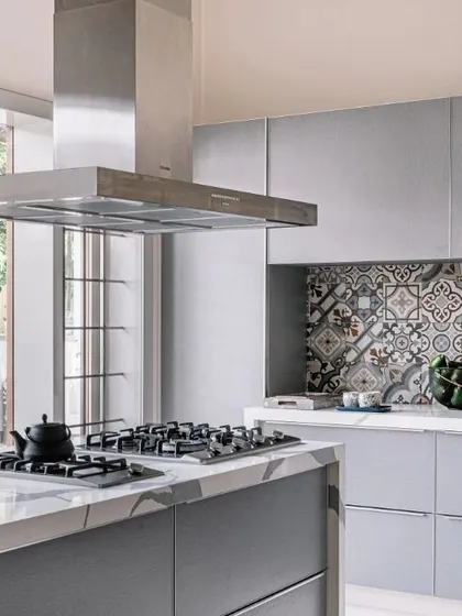 A closer look at the kitchen, where the patterned backsplash adds a touch of traditional charm to the modern, sleek cabinetry. The view to the outside greenery remains a key feature of the space.