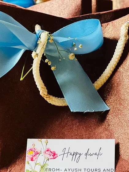A close-up of the custom 'Happy Diwali' tag and blue ribbon on one of the paper gift bags.