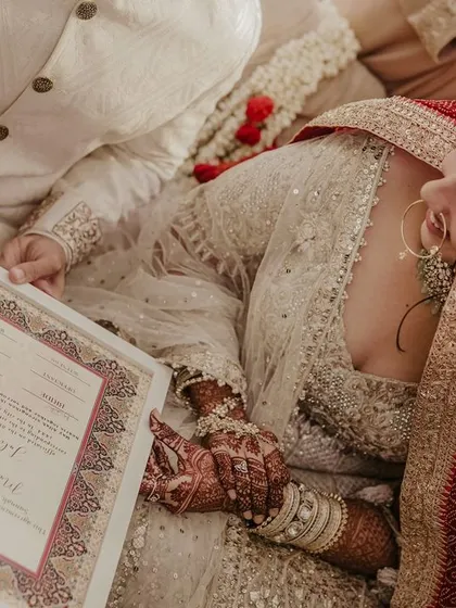 The couple signs their Nikah contract, their hands close together, symbolizing their new partnership.