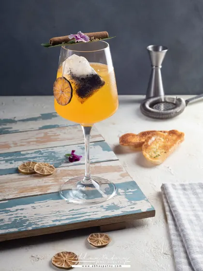 A sophisticated cocktail in an elegant wine glass. The styling is minimal to emphasize the drink's color and the artistic garnish.