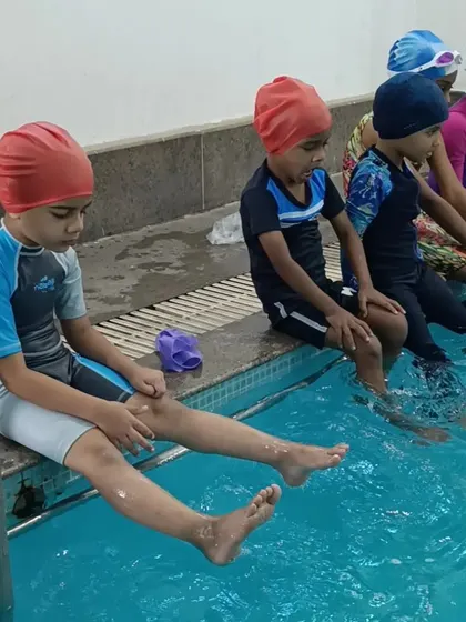 Young swimmers taking a break on the pool's edge, ready for their next instruction during a summer camp session.
