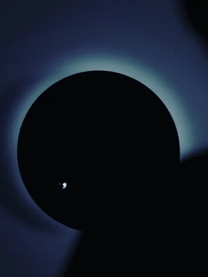 A dramatic, artistic photograph of the STORY clock in the dark. The levitating sphere catches the light, resembling a moon orbiting a planet, perfectly illustrating its concept of visualizing time's journey.