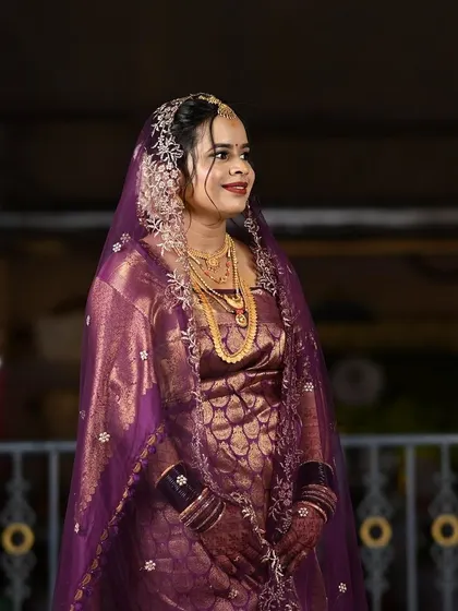 A portrait of a bride in a purple saree with a delicate veil. Her makeup is soft and elegant.