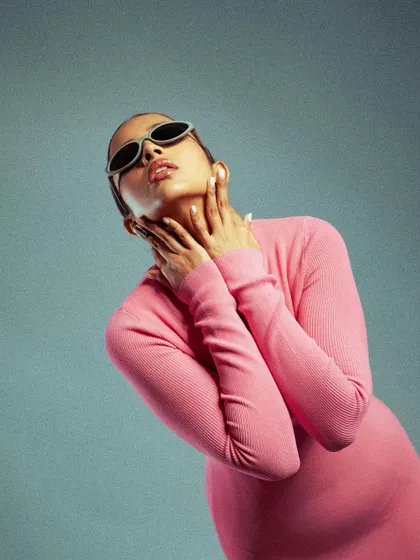 A high-fashion studio shot with a pop of color. The model's pose and the stark lighting against a cool blue background create a modern, editorial feel.