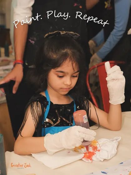 A young girl is engrossed in her tie-dye project with the words "Paint. Play. Repeat." overlaid, capturing the essence of my kids' events.