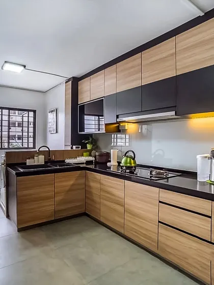 This L-shaped kitchen expertly blends natural wood-textured cabinets with sleek black upper units. The under-cabinet lighting highlights the workspace on the black countertop, creating a modern yet warm kitchen environment.