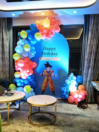A powerful Dragon Ball Z themed birthday decoration. This setup features a large backdrop of Goku, framed by a dynamic balloon arrangement in the character's signature orange and blue colors.