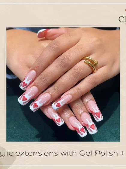 An amped-up French manicure. These long, square-tipped acrylics feature a modern French design with a flame shape filled with sparkling red hearts.