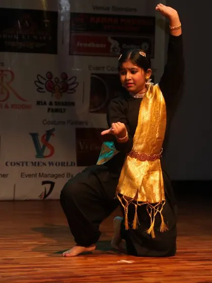 A solo performer in a graceful pose during her classical dance routine.