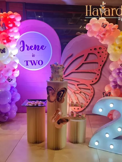 Another beautiful butterfly-themed party, this one for a second birthday. The decor features a large, elegant butterfly wing cutout and a soft, colorful balloon arrangement.