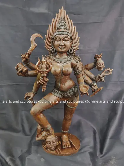 A standing form of the goddess Kalika, sculpted in wax. This depiction captures her dynamic energy, with multiple arms holding symbolic weapons and her foot resting on a vanquished demon.