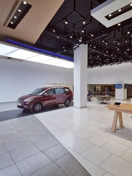 A featured car display area under a large, illuminated ceiling panel. This specific lighting treatment highlights the vehicle, making it the hero of the space and drawing immediate customer attention.