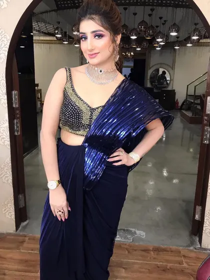 A full-length view of a stunning cocktail look. The bold purple and blue eye makeup makes a statement and pairs perfectly with the royal blue saree.