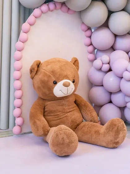 A giant, huggable teddy bear sits nestled within the pastel balloon decor, welcoming guests to the baby shower.