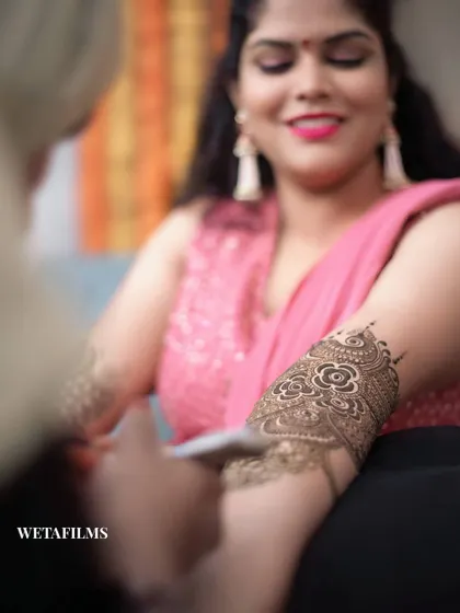 Capturing the intricate art of Mehndi. This shot focuses on the beautiful henna design being applied, a key part of the pre-wedding preparations and a symbol of joy and beauty.