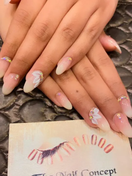 A soft and elegant ombre nail set with 3D floral accents. The nails are further embellished with small gold crystals at the cuticle and on the flower petals.