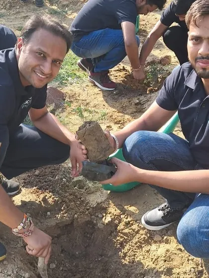 Two volunteers from Bacardi work together to plant a native sapling, placing rocks in the pit to help retain moisture in the dry, rocky soil.