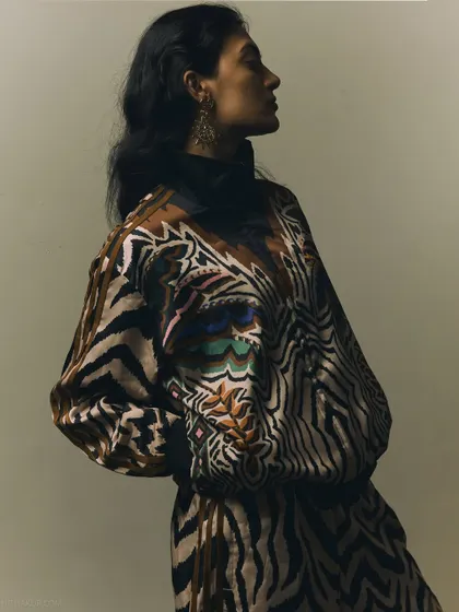A profile shot from the same series, highlighting the unique pattern of the outfit and the model's elegant silhouette.