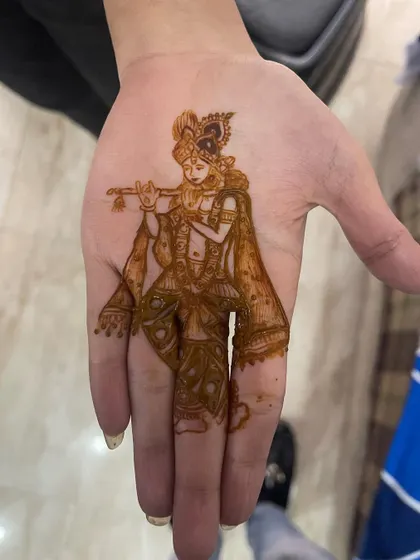 A full-figure portrait of Lord Krishna playing his flute. This design covers the entire palm and is filled with intricate details on his clothing and jewelry.