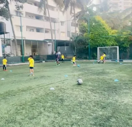 A wide shot of a training session, showing players spread out and engaged in various activities.